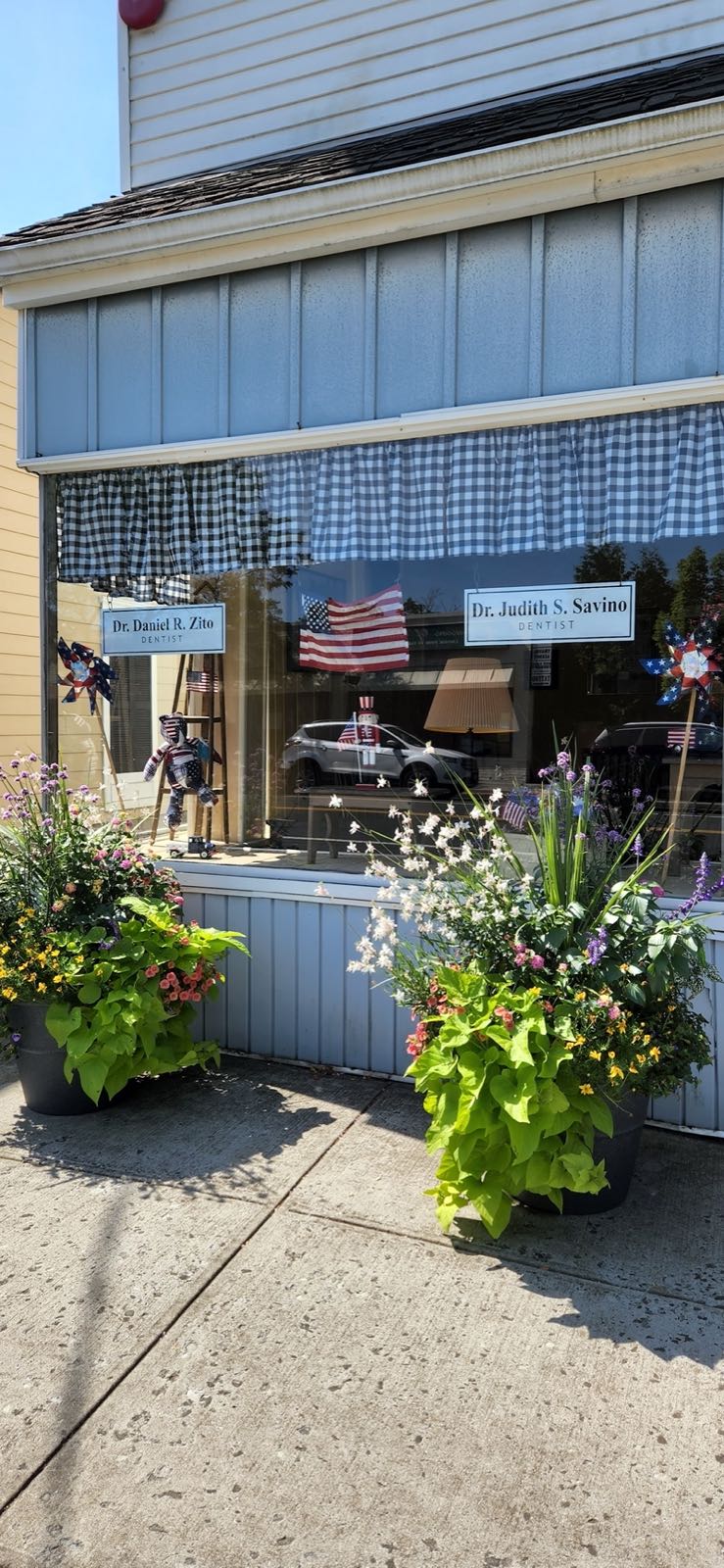 The Savino dental office storefront on Main Street with summer flowers and flags